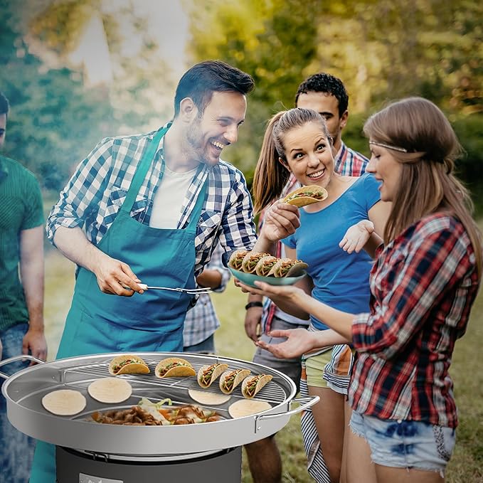 Group of people enjoying a barbecue outdoors with food on a grill and plates.